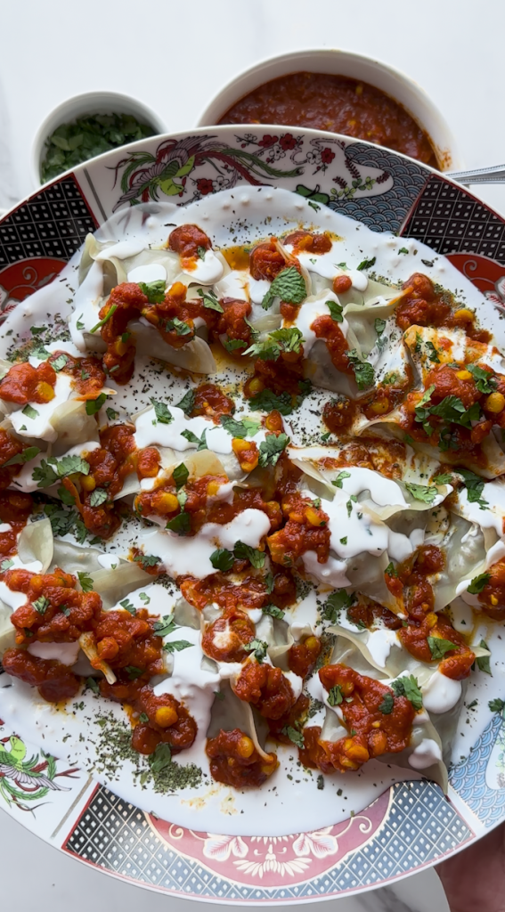 a plate full of Mantu with a sauce being poured over it